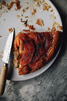 a piece of pizza sitting on top of a white plate with a knife next to it