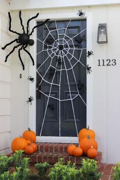 halloween decorations on the front door of a house with spider webs and pumpkins