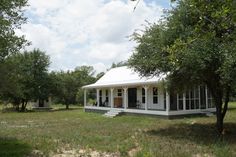 a small white house sitting on top of a lush green field