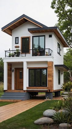 a white house with wood trim and windows on the second floor is surrounded by greenery