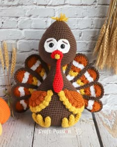 a crocheted turkey sitting on top of a table next to some wheat stalks