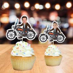 two cupcakes with an image of a motorcyclist on one and a motorcycle on the other