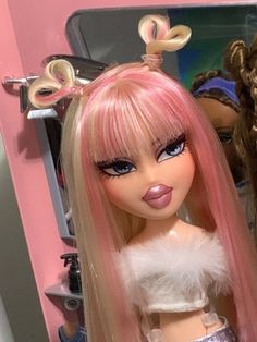 a close up of a doll with pink hair