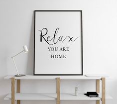 a black and white poster with the words relax you are home on top of a shelf