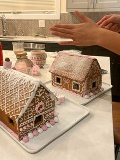 two gingerbread houses sitting on top of white plates