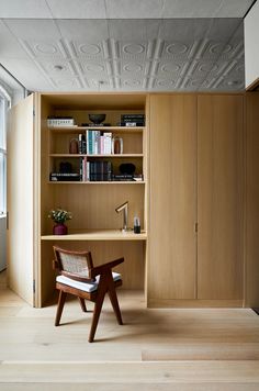 a chair sitting on top of a wooden floor next to a book shelf