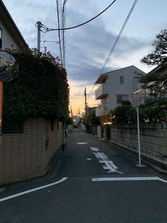 an empty street with buildings on both sides and trees in the background at sunset or dawn