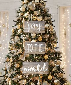 a christmas tree decorated with gold ornaments and wooden signs that say joy to the world