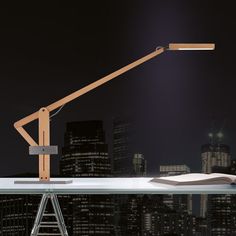 a desk lamp sitting on top of a table in front of a cityscape