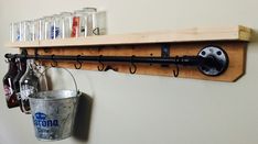 a wooden shelf with metal buckets hanging from it's sides and bottles on the wall