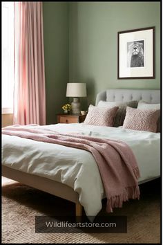 a bedroom with green walls, white bedding and pink throw pillows on the headboard