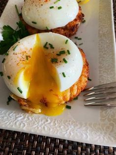 two eggs are on top of an english muffin with melted cheese and parsley