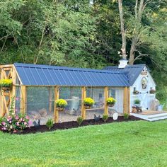 a small chicken coop in the middle of a grassy area with flowers growing on it