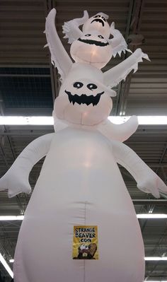 an inflatable white ghost with two heads and arms is suspended from the ceiling