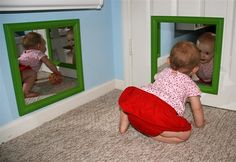 two toddlers are playing with their reflection in the mirror