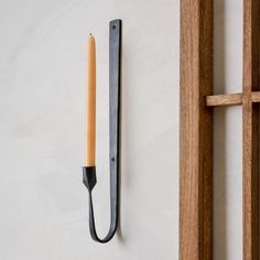 a candle is hanging on the wall next to a window frame with an iron hook