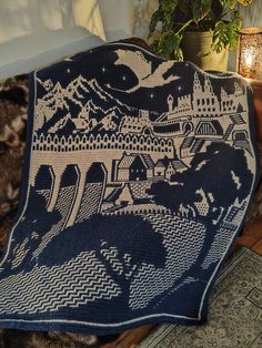 a blue and white blanket sitting on top of a bed next to a potted plant