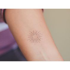 a woman's arm with a small sun tattoo on the left side of her arm