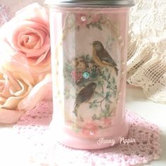 there is a pink vase with two birds on it next to some lace and flowers