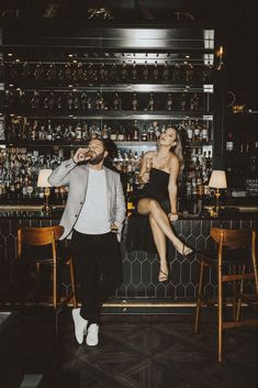 a man and woman sitting at a bar with their feet up on the bar stools