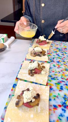 a person preparing food on top of some tortilla wrappers with toppings