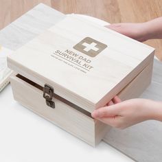 someone is opening up a wooden box on top of a table next to a book