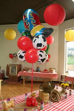 a table topped with lots of balloons and other items on top of a checkered table cloth