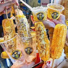 several people holding up corn on the cob sticks and cups with drinks in them