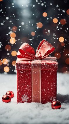 a red gift box with a bow on it in the snow