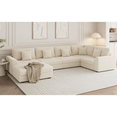 a living room with a large white sectional couch and rug on the floor in front of it