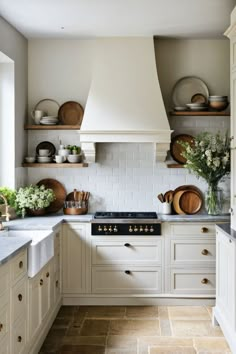 a kitchen with white cabinets and open shelving above the stove top is filled with pots and pans