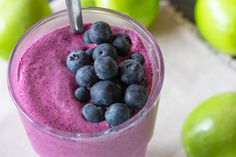 a smoothie is garnished with blueberries and green apples