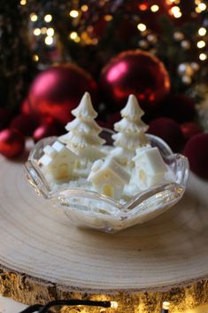 a glass bowl filled with food on top of a wooden table next to christmas decorations