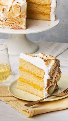 a piece of cake on a plate with a fork next to it and a glass of wine in the background