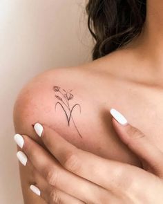 a woman's shoulder with a small flower tattoo on the left side of her arm