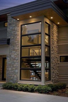 a modern house is lit up at night with lights on the windows and stairs leading to the upper floor