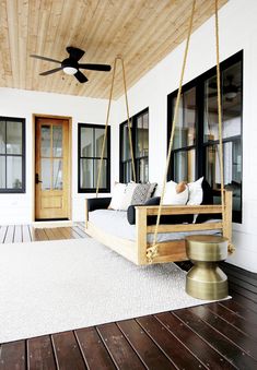 a porch swing with pillows on it