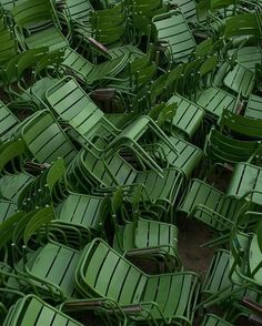 many green plastic chairs are stacked together