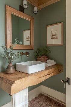 a bathroom sink sitting under a mirror on top of a wooden counter next to a potted plant