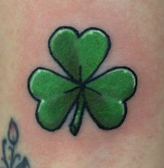 a green four leaf clover tattoo on the leg