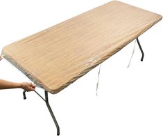 a person is holding an ironing board on top of a wooden table with metal legs