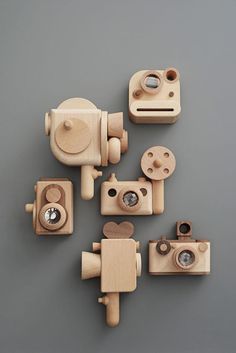 four wooden toy cameras sitting next to each other on a gray surface with white background