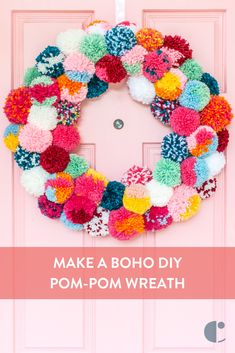 a pink door with a colorful pom - pom wreath hanging on it's side