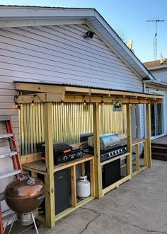 an outdoor bbq area with grill and ladder