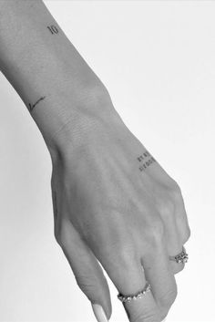 a woman's hand with two rings on it and the word love is written on her wrist