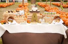 a table topped with hay bales covered in pumpkins and other decorations on top of a field