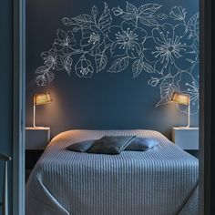 a bedroom with blue walls and white flowers on the wall