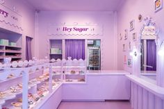 the inside of a store with purple walls and shelves filled with cupcakes on display