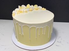 a yellow cake with white icing and flowers on top