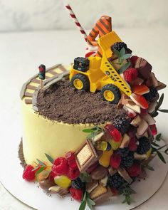 there is a cake decorated like a construction truck on top of the cake with berries and candy